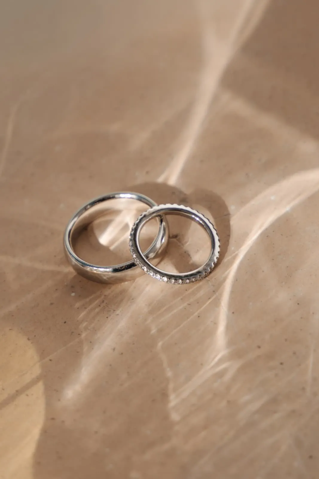 Dos alianzas de boda sobre piedra con reflejos de luz