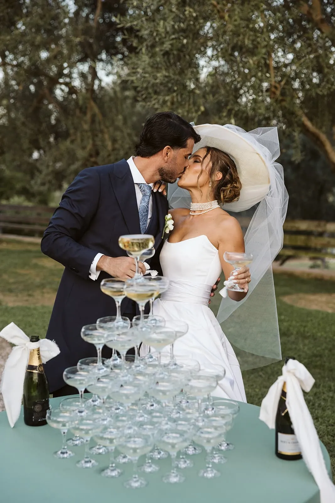Novios besándose junto a una torre de copas de champán